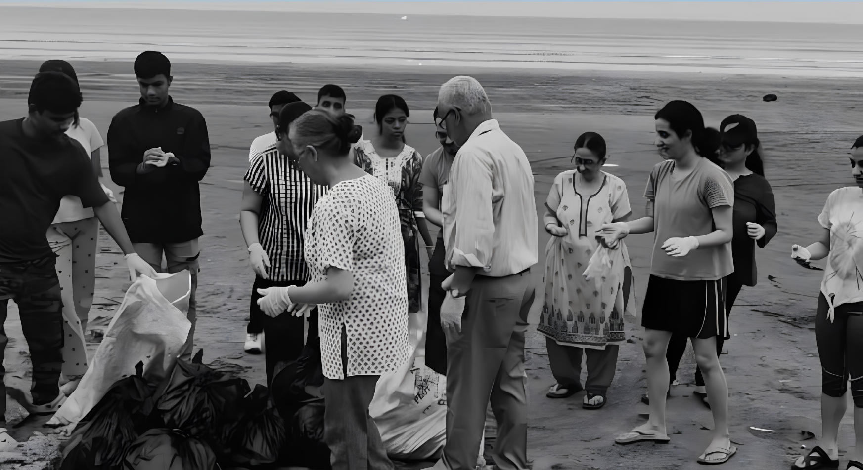 Members and sponsored students collecting litter into bags during a Mumbai beach clean-up